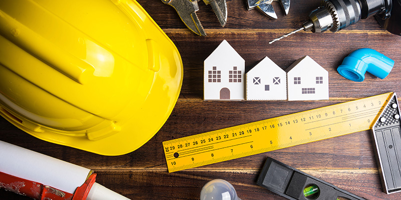 paper white house toy and construction tools on wooden backgroun